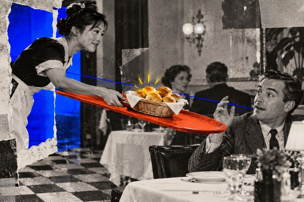 A server presenting a basket of dinner rolls on a bright red tray to a surprised diner